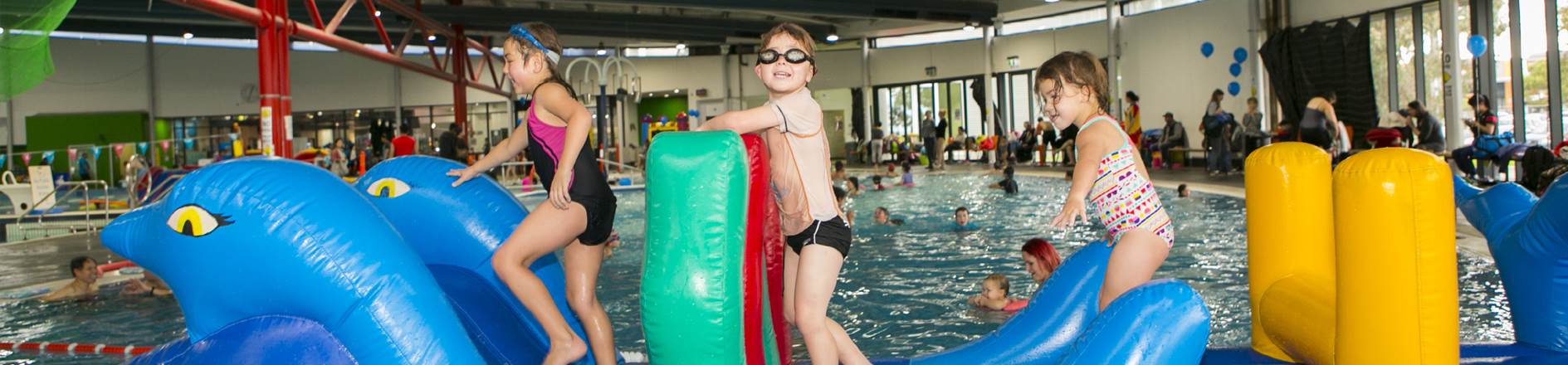 Kids playing on an inflatable pool toy. 