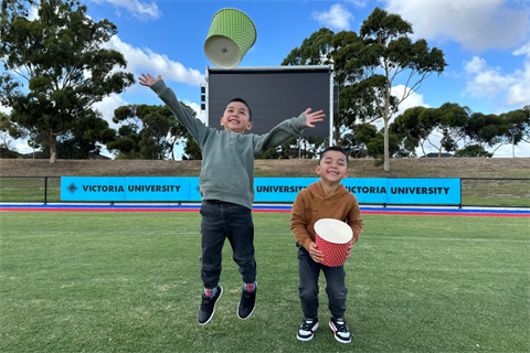 Two young boys standing on skinner reserve in front of the screen jumping in the air with popcorn boxes