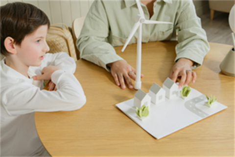 A child sitting and looking at a model of a town and a wind turbine