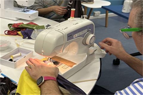 A person sewing a piece of fabric using a sewing machine